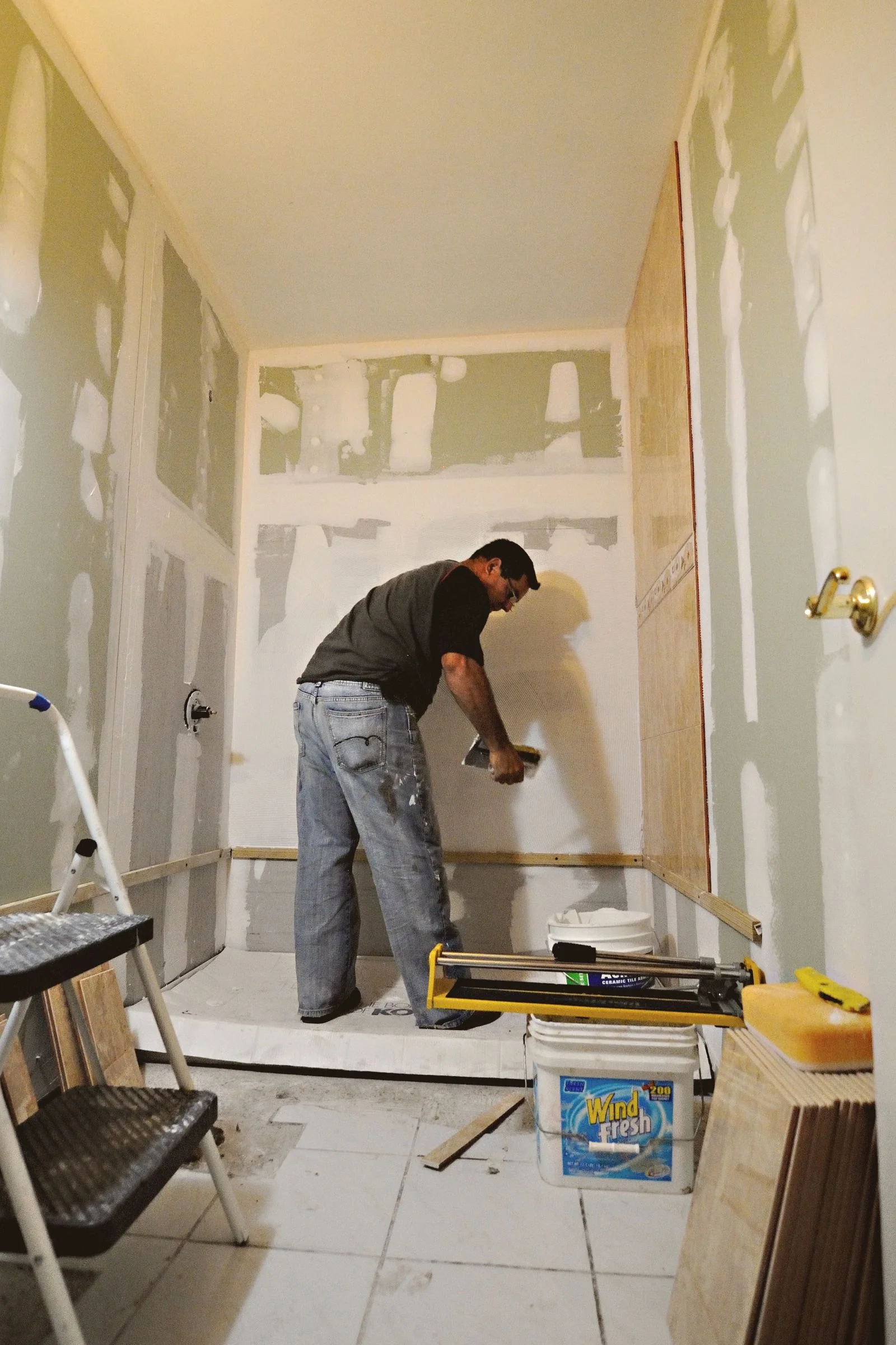 Worker applying joint compound to drywall in a bathroom renovation